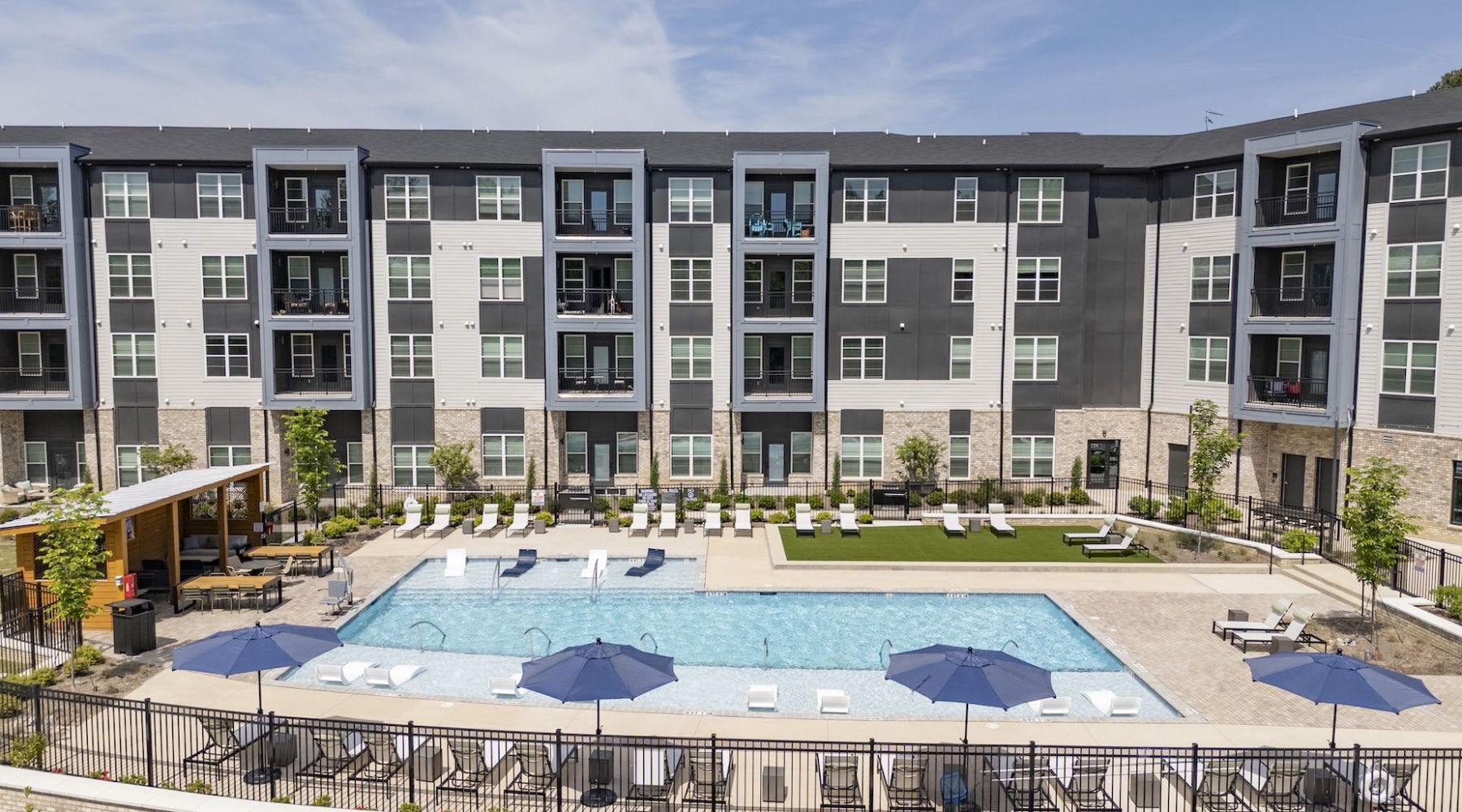 Swimming pool with lounge chairs and picnic tables at Gladwen apartments in Wendell, NC
